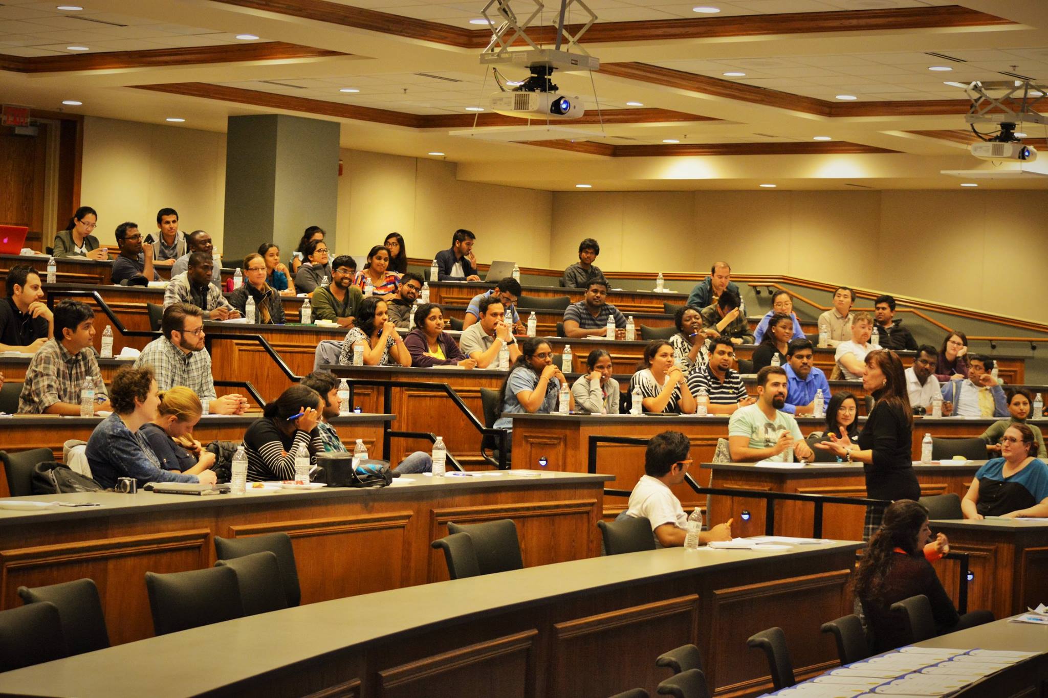 Students seated in a meeting space listening to a presenter.