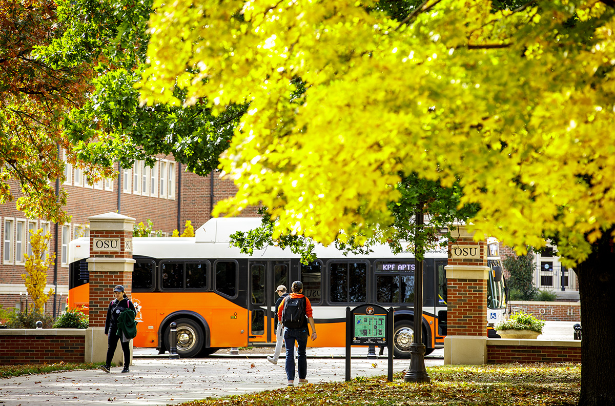 People waling up to a bus parked on the OSU campus.