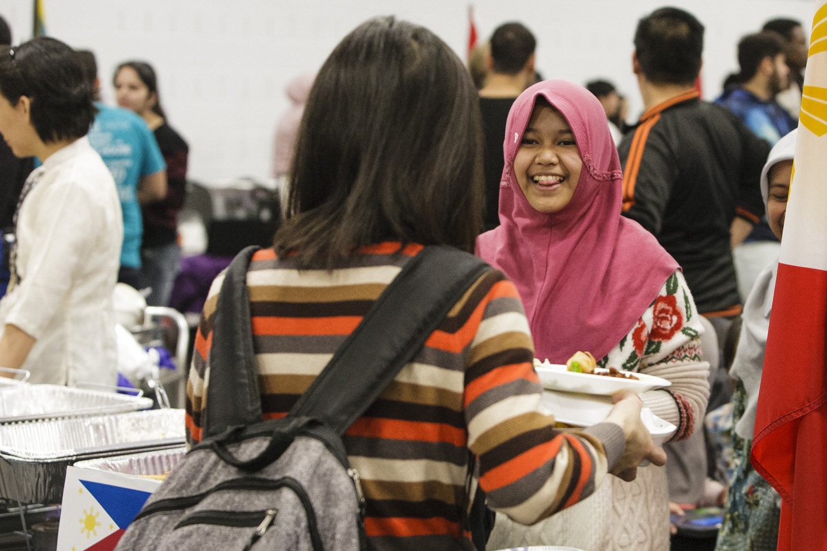 Two women holding plates of food at a social event on campus.