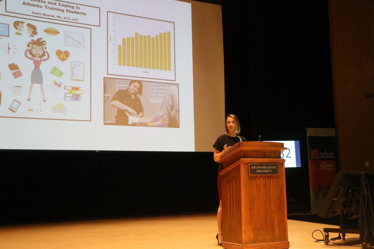 Student speaking at podium with a slide behind her.