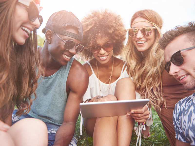 A group of people smiling and looking at a tablet.