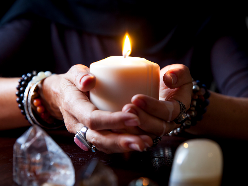 A lit candle held in cupped hands.